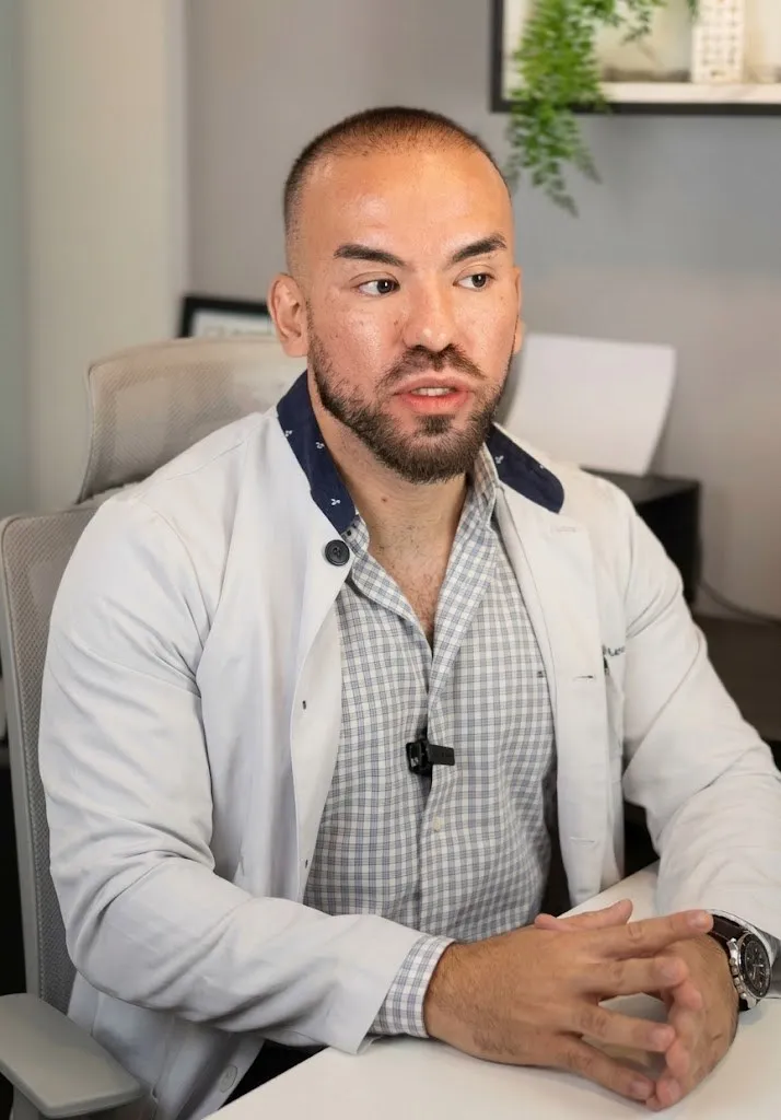 Dr. José Jorge Viana, de jaleco, sentado à mesa do consultório